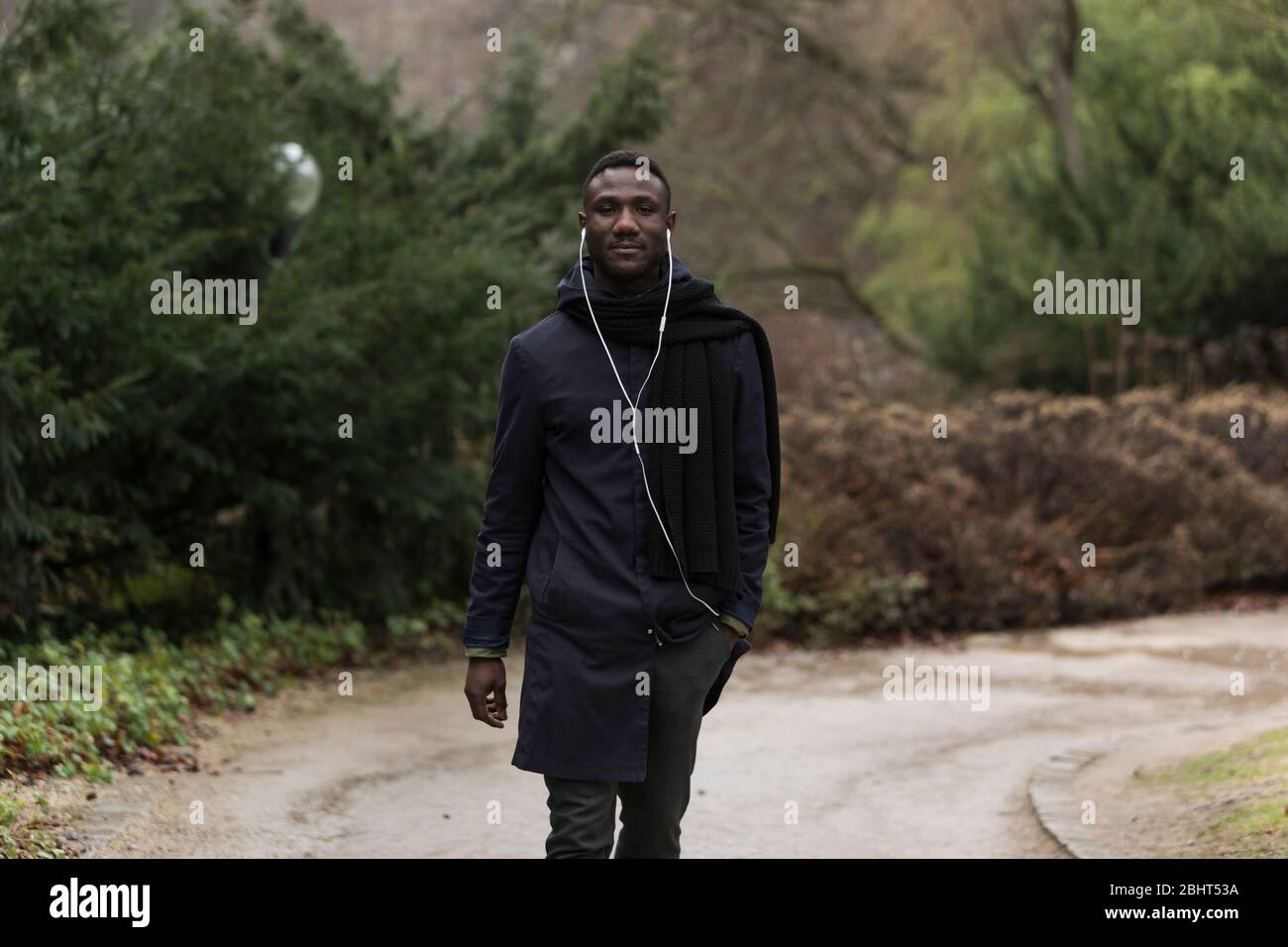 Junge schwarze bedeuten mit Kopfhörern auf Parkstraße Blick auf Kamera. Du Viertellänge. Stockfoto