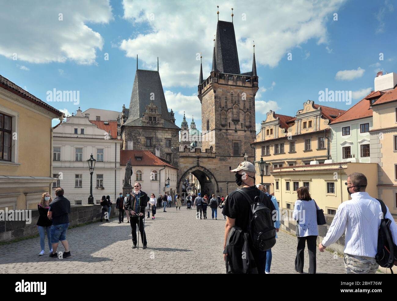 Prag, Tschechische Republik, 26. April 2020. Touristen mit Schutzmaske gehen nach dem Ausbruch der Kronenvirus-Pandemie im Frühjahr auf der mittelalterlichen Karlsbrücke Stockfoto Prag, Tschechische Republik, 26. April 2020. Touristen mit Schutzmaske gehen nach dem Ausbruch der Kronenvirus-Pandemie im Frühjahr auf der mittelalterlichen Karlsbrücke Stockfoto