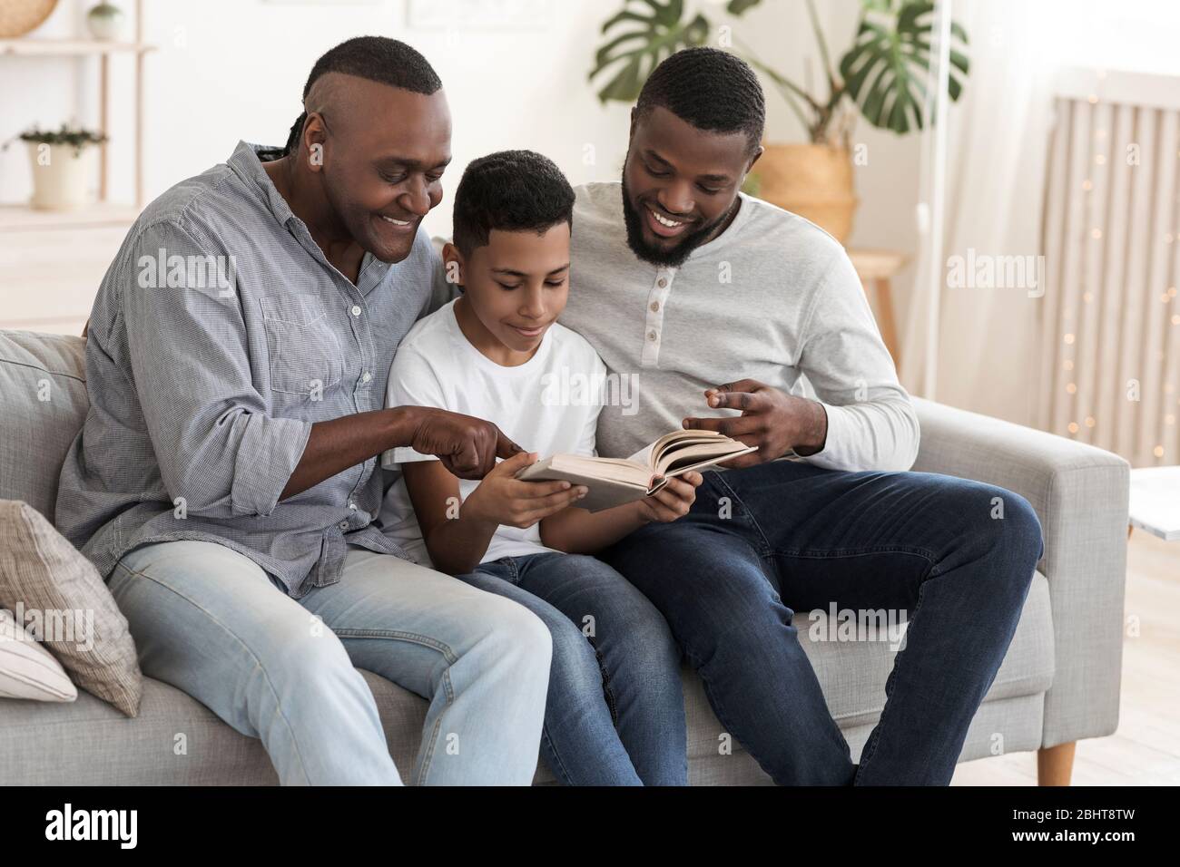 Kleiner Schwarzer Junge Lesebuch Mit Seinem Vater Und Großvater Zusammen Stockfoto