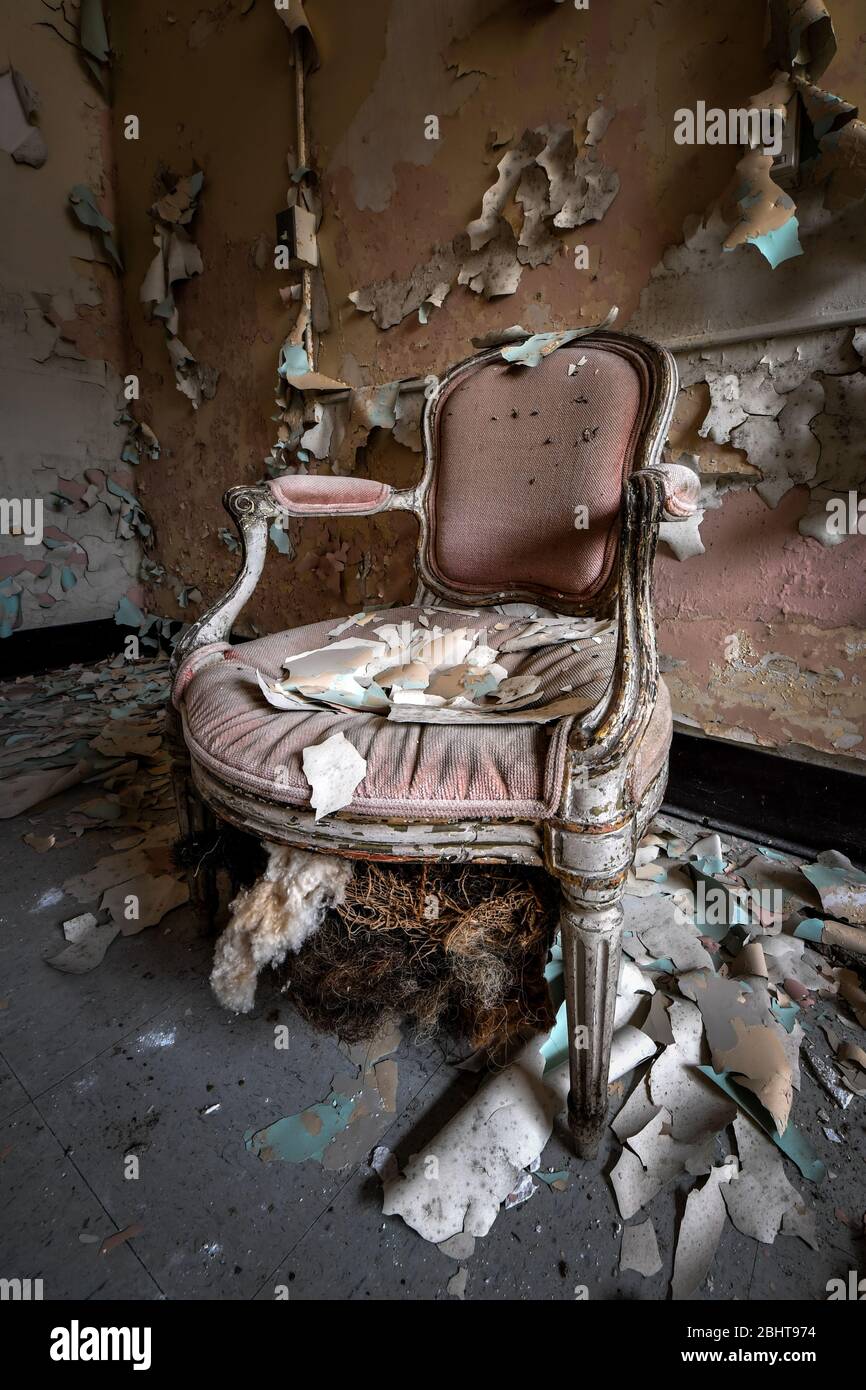 Kunstvoll-pinker Stuhl mit abblätternder Farbe in einem verlassenen Gebäude Stockfoto