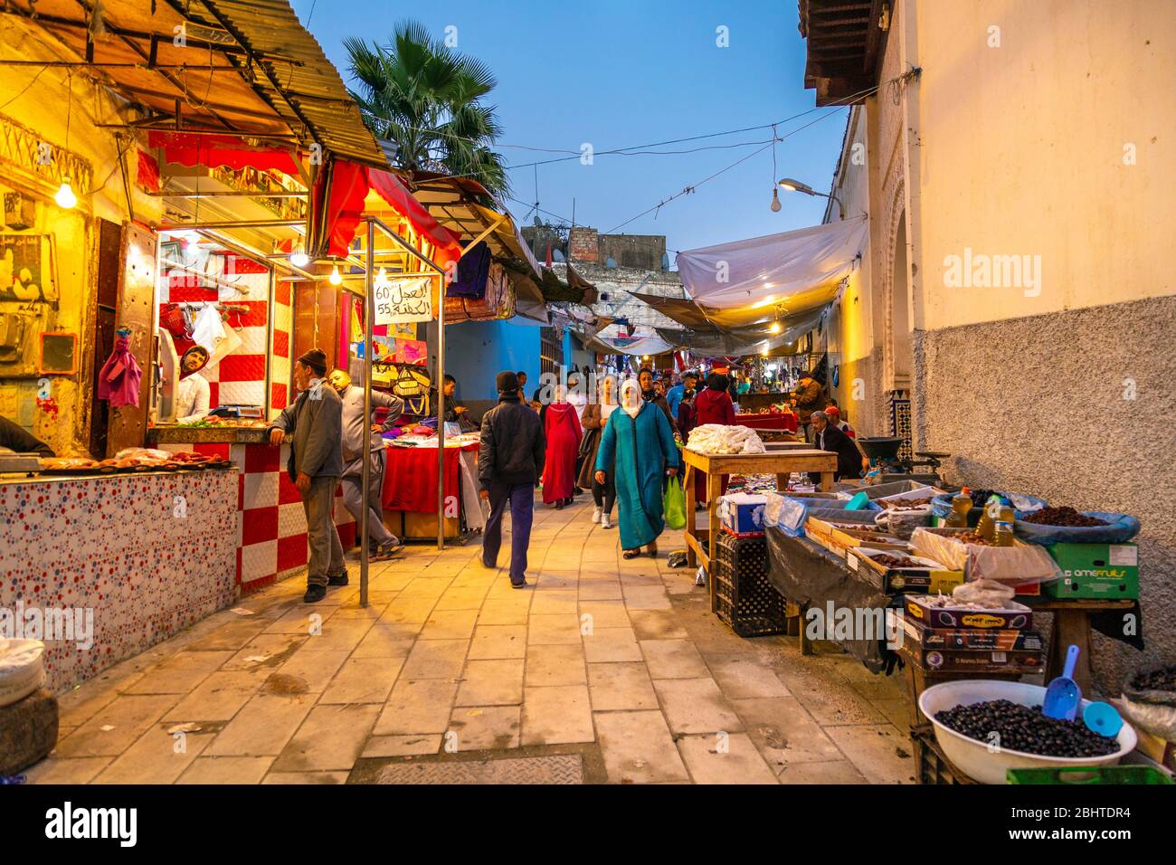 Eine schmale Straße mit Marktständen und Geschäften in den Souks in der Medina, Fes, Marokko Stockfoto