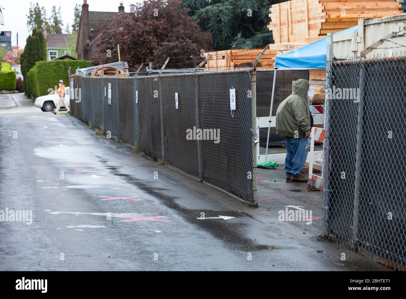 Ein Arbeiter kommt am Montag, den 27. April 2020, an einem Kontrollpunkt auf einer Baustelle in West Seattle an, während die Bauarbeiten wieder aufgenommen werden. Projekte mit geringem Risiko für Wohn- und Gewerbebauten müssen die COVID-19-spezifischen Sicherheitspraktiken für den Arbeitsplatz einhalten, um wieder aufgenommen zu werden. Stockfoto