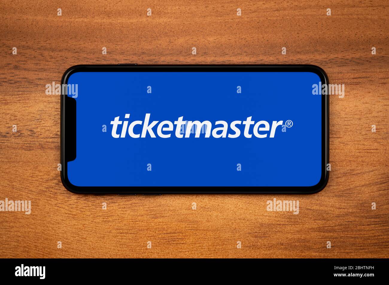 Ein Smartphone mit dem Ticketmaster-Logo liegt auf einem einfachen Holztisch (nur redaktionelle Verwendung). Stockfoto