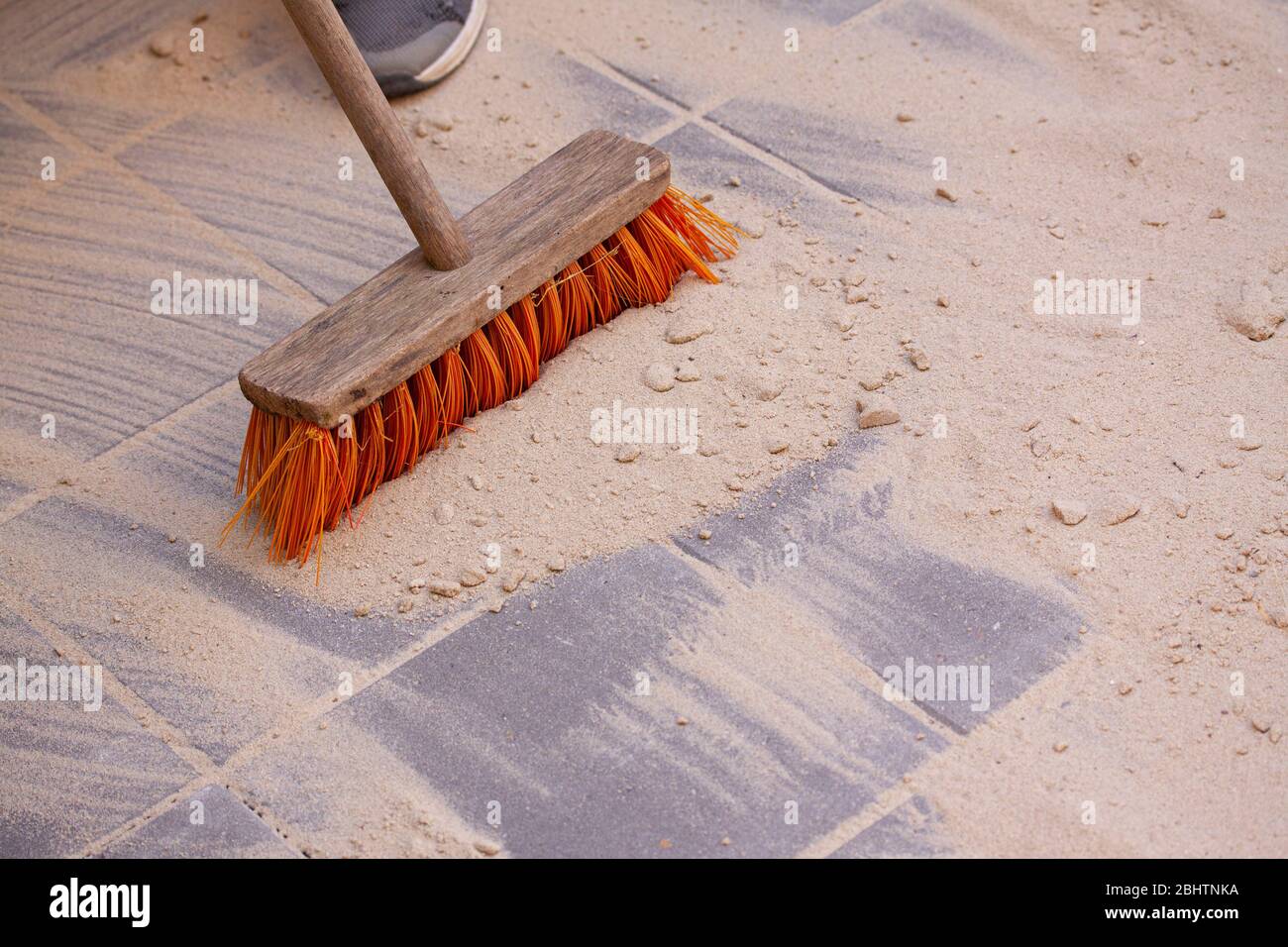 Sand über die Oberfläche von Pflastersteinen oder Fliesen und fegen sie in  die Räume mit einem Besen. Nahaufnahme des Bildes Stockfotografie - Alamy