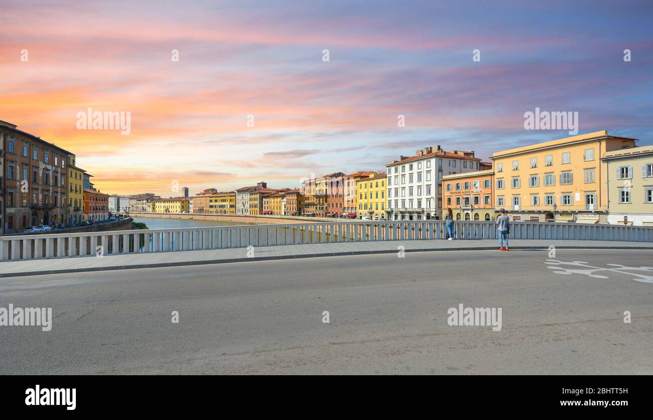 Ein Paar genießt den Sonnenuntergang über dem Arno in der Stadt Pisa, Italien, in der Region Toskana. Stockfoto