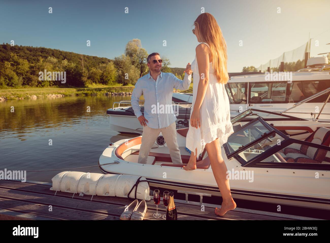 Mann lädt eine Frau zu seinem Motorboot im Flusshafen sitzen Stockfoto