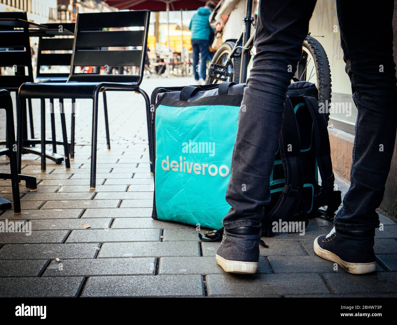 Paris, Frankreich - Feb 23, 2019: Großer Platz Deliveroo Platz Thermobag vor dem Restaurant Eingang mit Terrasse Stühle und Kunden in der Nähe Stockfoto