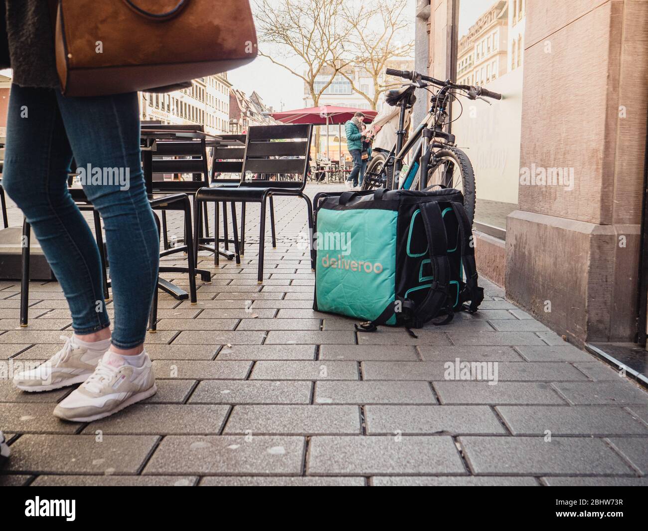 Paris, Frankreich - Feb 23, 2019: Großer Platz Deliveroo Platz Thermobag vor dem Restaurant Eingang mit Terrasse Stühle und Kunden in der Nähe Stockfoto