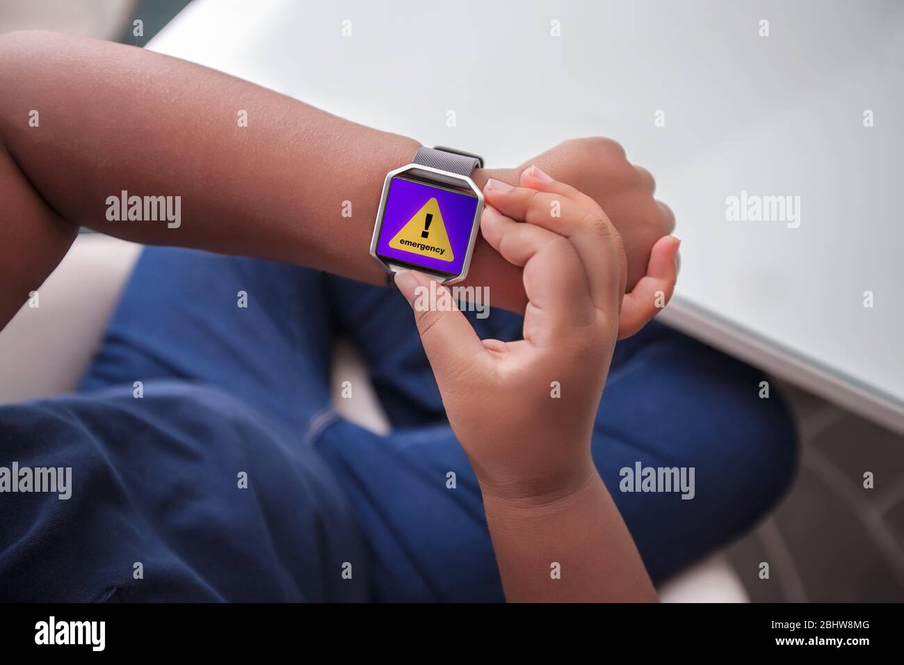 Eine Notfallbenachrichtigung, die auf einer drahtlosen Smart-Armbanduhr empfangen wird, während sie vor einem Schreibtisch sitzt. Stockfoto