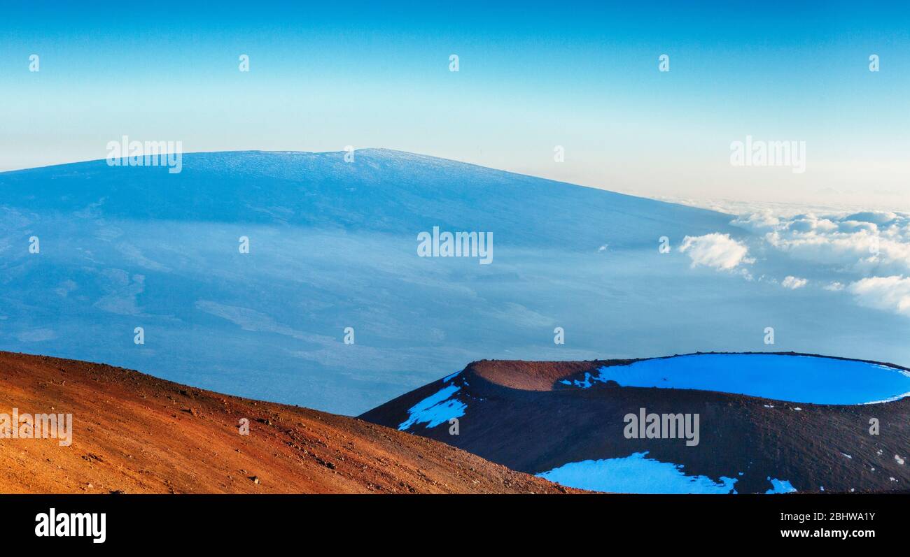 Blick über den Schlackenkegel auf dem Mauna Kea zum Mauna Loa Gipfel im Schnee auf Hawaii Island. Stockfoto