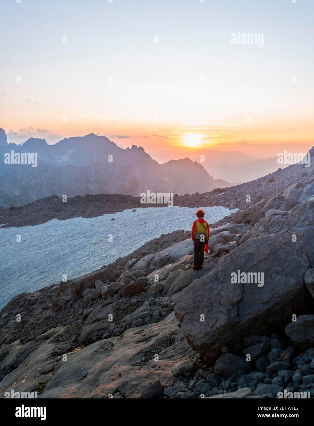 Wanderer steht in felsigem alpinem Gelände und blickt auf Sonnenuntergang über Gosaukamm mit Berggipfel Bischofsmuetze, Abendstimmung, Salzkammergut, Obere Stockfoto