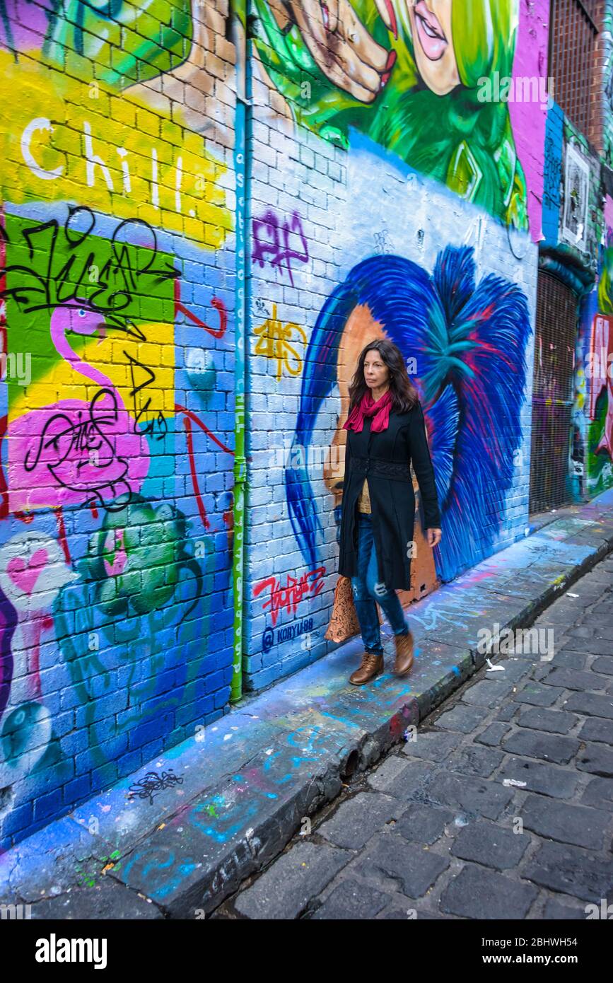 Touristen, die die Hosier Lane entlang laufen, bewundern einen der berühmtesten und beliebtesten Street Art Lane Ways in Melbourne. Stockfoto