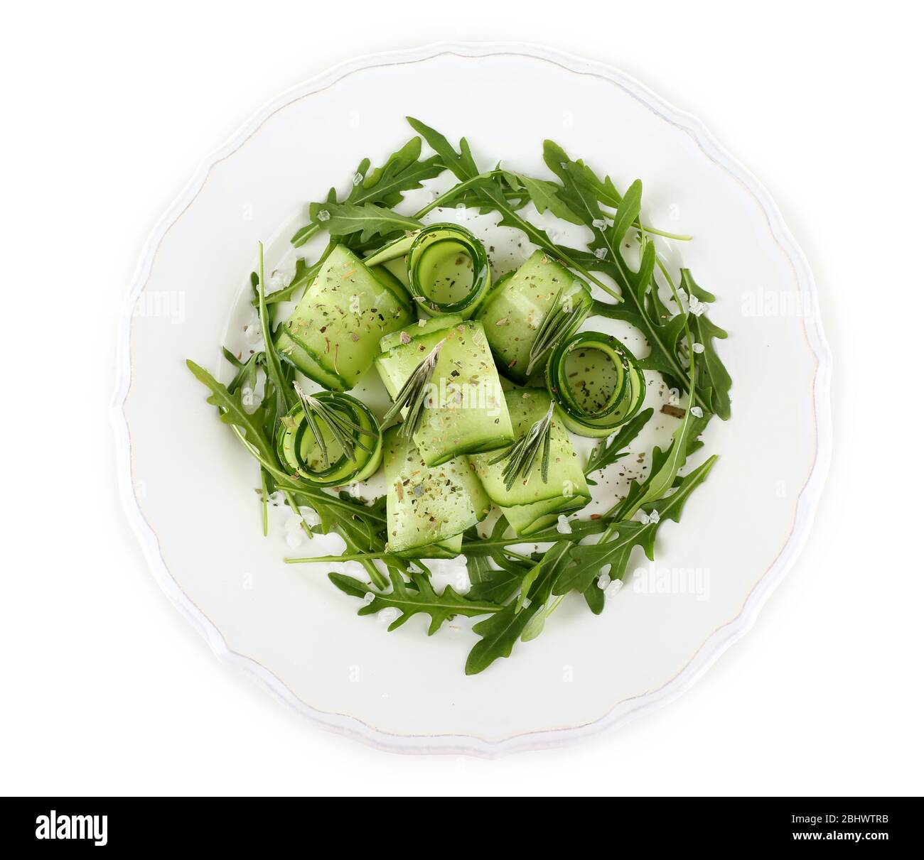 Teller mit grünem Salat mit Gurke, Rucola und Rosmarin auf weiß isoliert Stockfoto