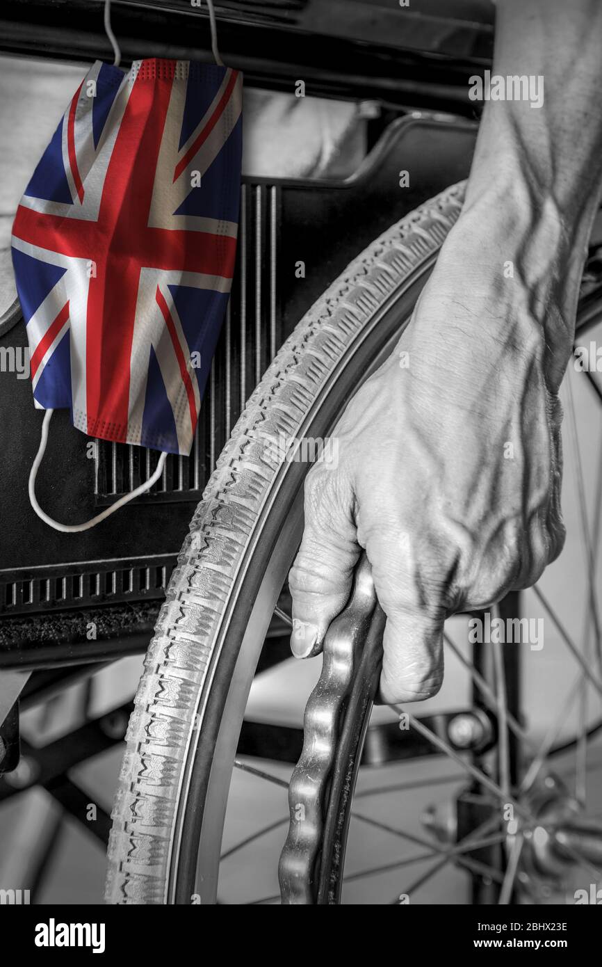 Senior im Rollstuhl im Pflegeheim in schwarz und weiß mit aufhängender Gesichtsmaske mit britischer Flagge in Farbe. Konzept des Covid-19 Coronavirus Ausbruch in Großbritannien n Stockfoto