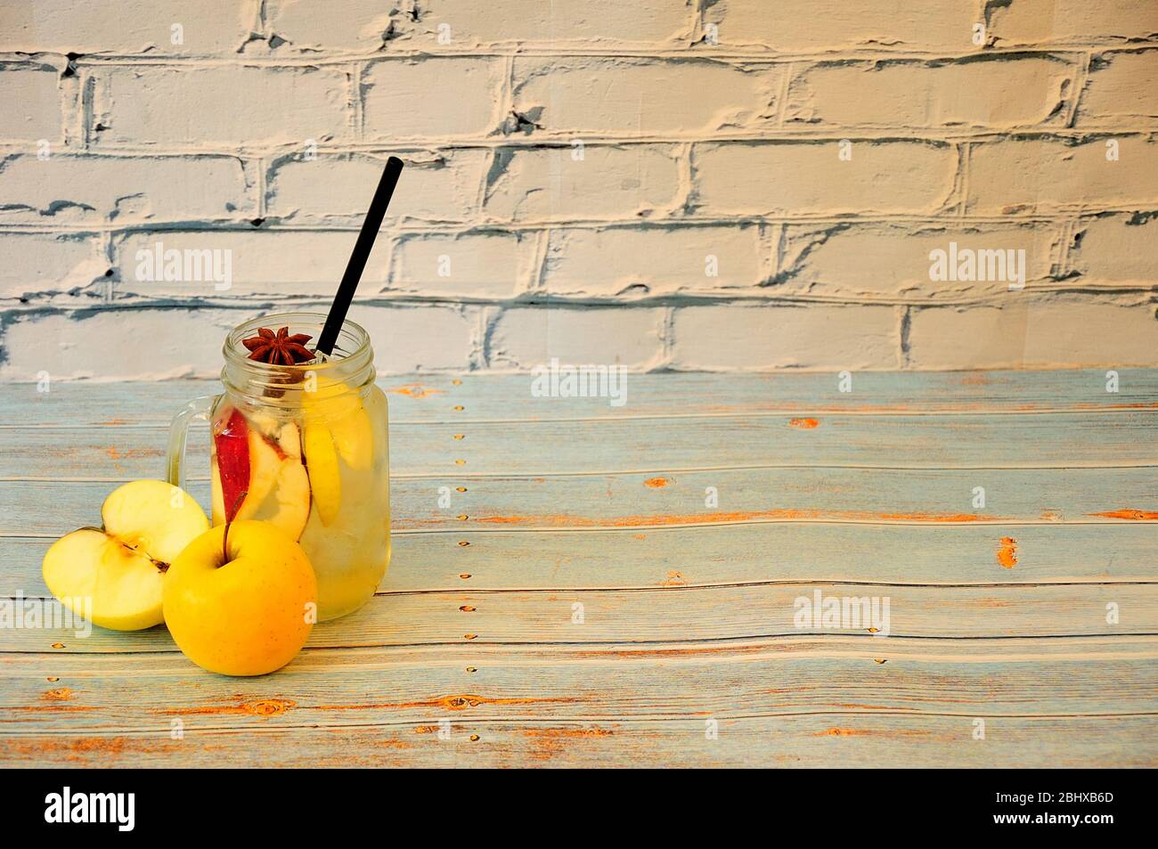 Ein Glas Saft mit Eis und Scheiben Obst und Anis, neben zwei gelben ...