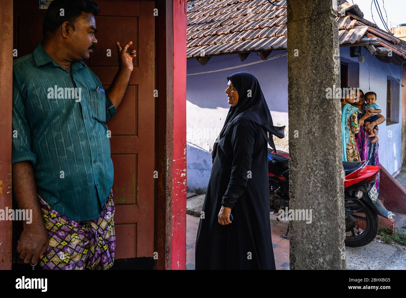 Nachbarn sprechen vor ihren Häusern, Kochi, Indien Stockfoto