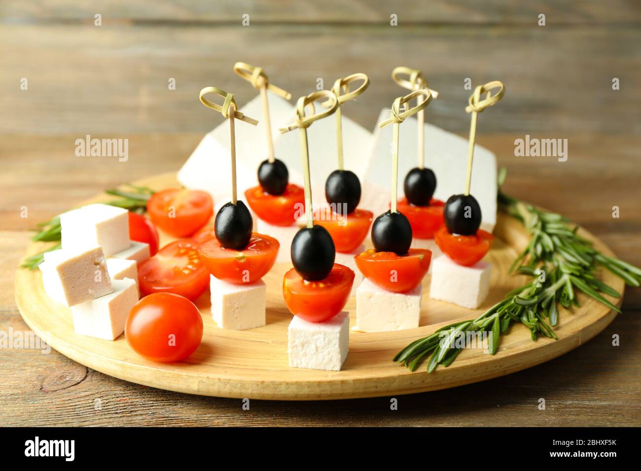 Käsekanaffen mit Kirschtomaten und Oliven auf Holztablett aus nächster Nähe Stockfoto
