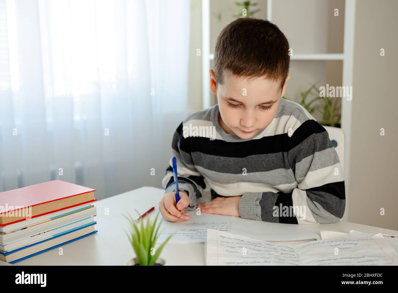 Porträt des Schuljungen zu Hause Schreiben am Tisch. Zurück zur Schule Stockfoto