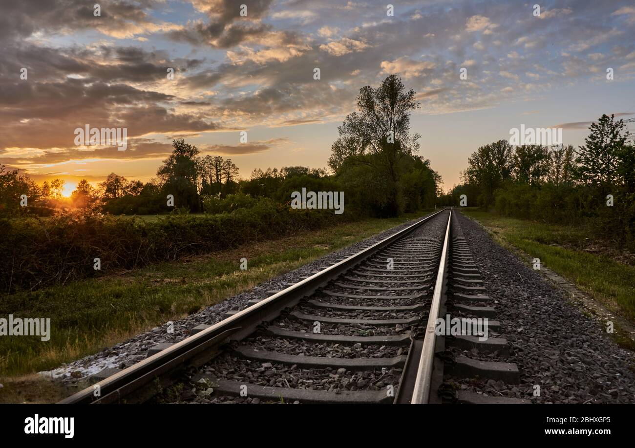 Bahngleise vor der Natur und einem bewölkten Sonnenuntergang Himmel. Hintergrund des Schienenverkehrs Stockfoto