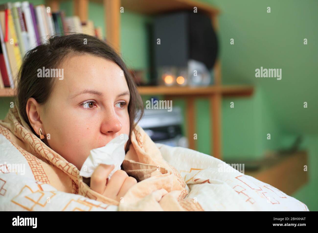 Hübsche junge Brünette Frau, die ihre Nase durch weißes Taschentuch, Krankheitskonzept, Halsschmerzen bläst Stockfoto