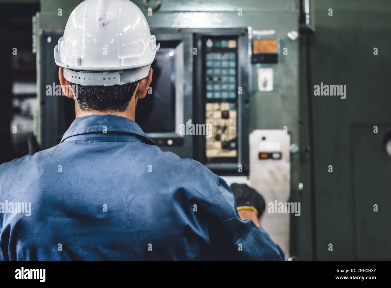 Der Arbeiter in der Nahaufnahme betreibt die Maschine, die Arbeitsbranche mit hoher Qualifikation und Sicherheitskleidung. Stockfoto
