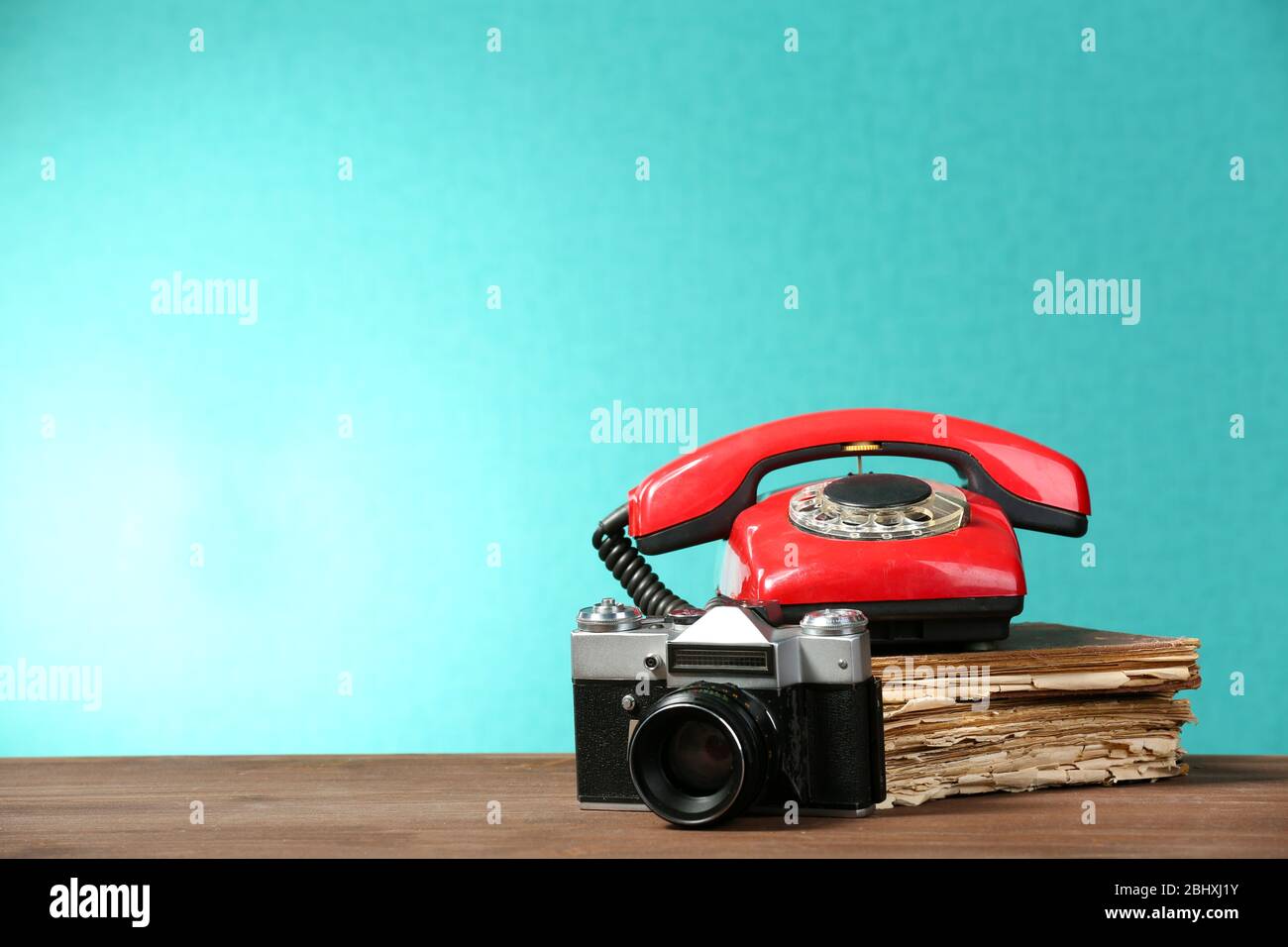 Retro-Kamera mit altem Buch und Telefon auf Tisch auf grünem Hintergrund Stockfoto
