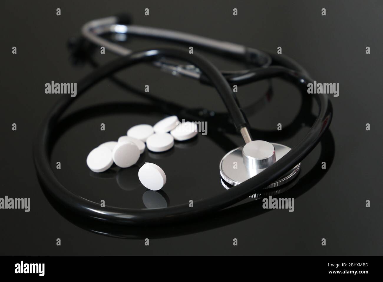 Gesundheit und Kardiologie, Stethoskop und weiße Pillen auf dunklem Glastisch. Konzept der Diagnose, Behandlung von Herzerkrankungen Stockfoto