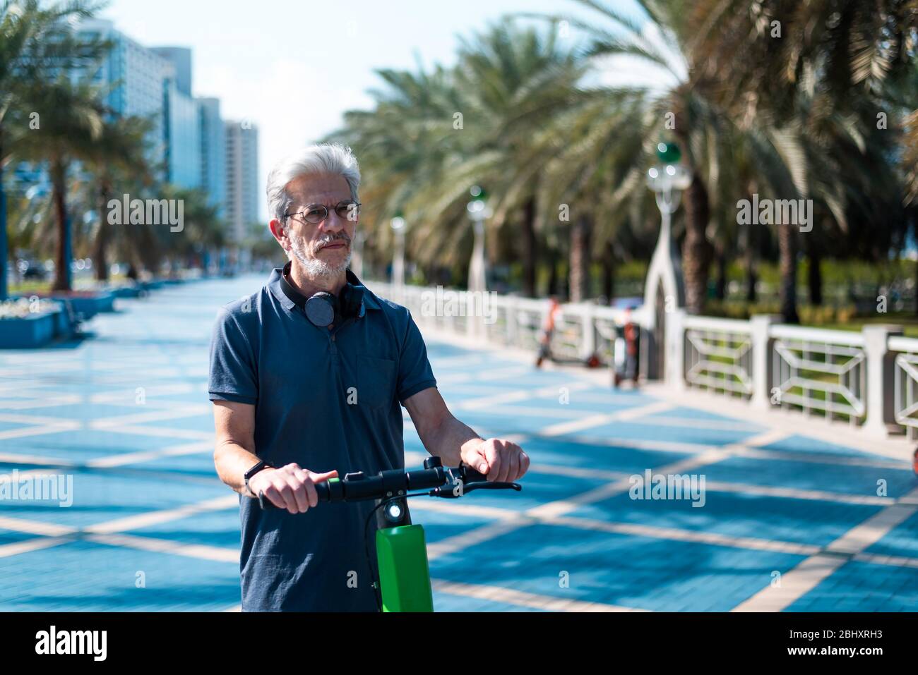 Senior mit Elektroroller für den Transport in einer modernen Stadt Umgebung. Gesunde Senioren Lebensstil im Freien Stockfoto
