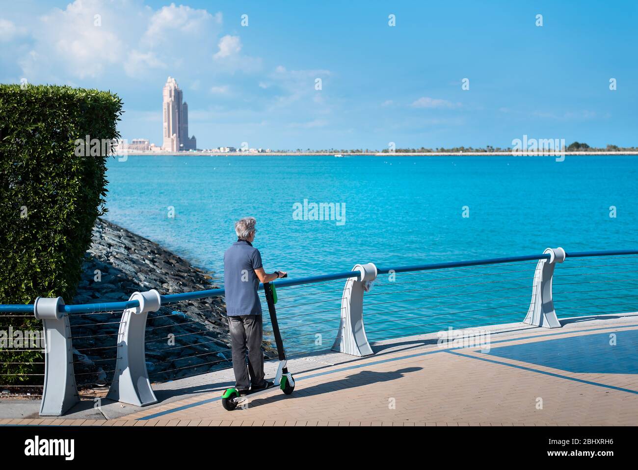 Älterer Mann mit Elektroroller für den Transport am Meer. Gesunde Outdoor Senior Lifestyle Stockfoto