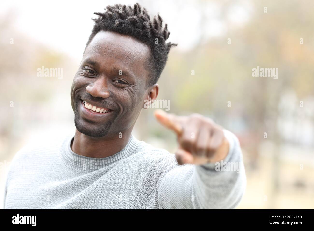 Fröhlicher schwarzer Mann zeigt auf Sie und schaut auf Kamera im Freien in einem Park Stockfoto