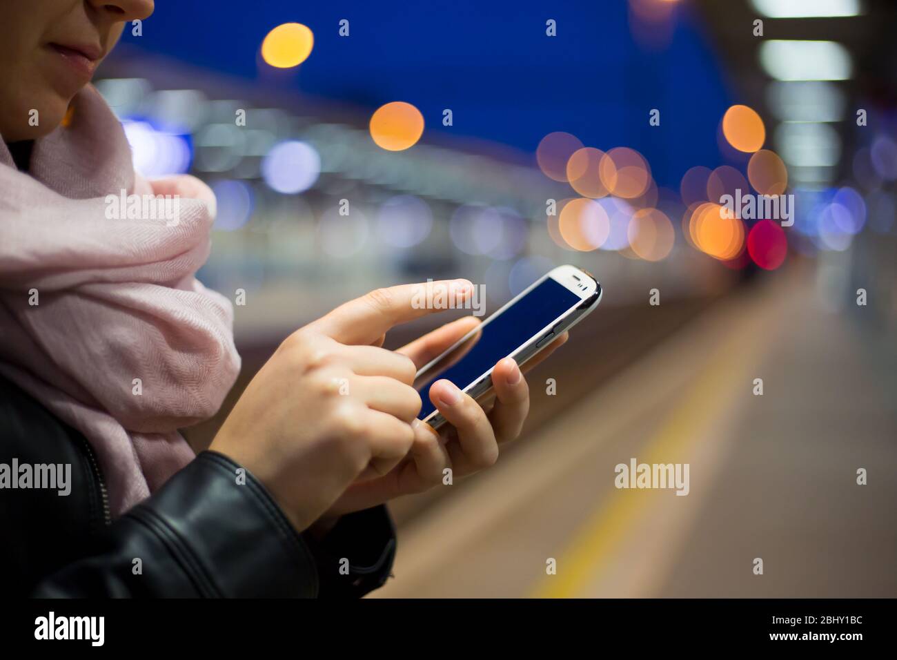 Junge Frau ruft am frühen Morgen auf einem Handy am Bahnhof, Technologiekonzept Stockfoto