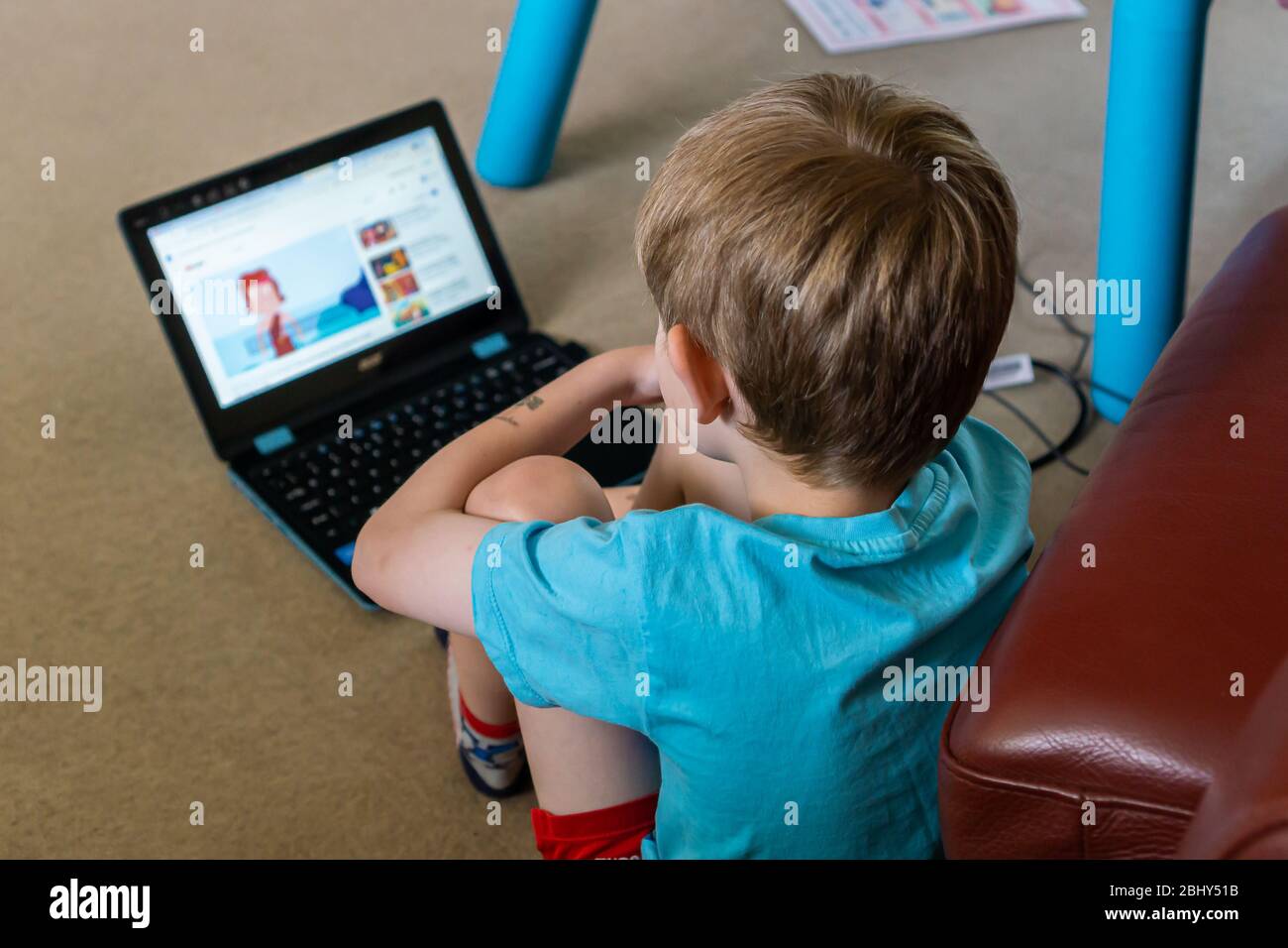 Kaukasischer Junge, der mit einem Laptop in seinem Schlafzimmer für die Hausschulausbildung studiert, Großbritannien Stockfoto