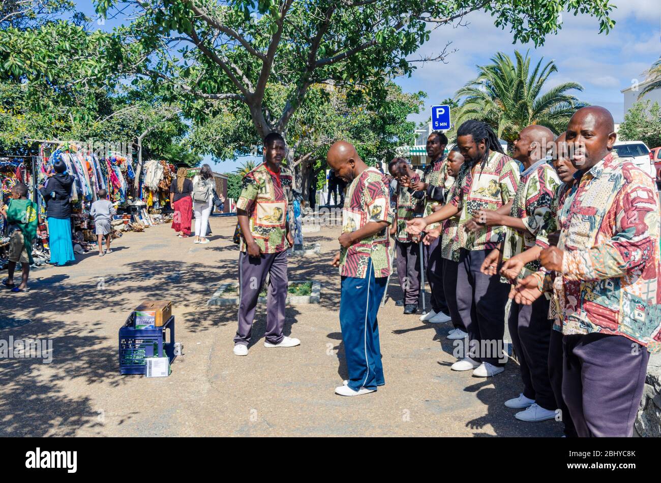 Gruppe afrikanischer Musiker und Tänzer, die auf einem Parkplatz in der Nähe der Touristenattraktion Boulders Beach Kapstadt Südafrika busteln Stockfoto