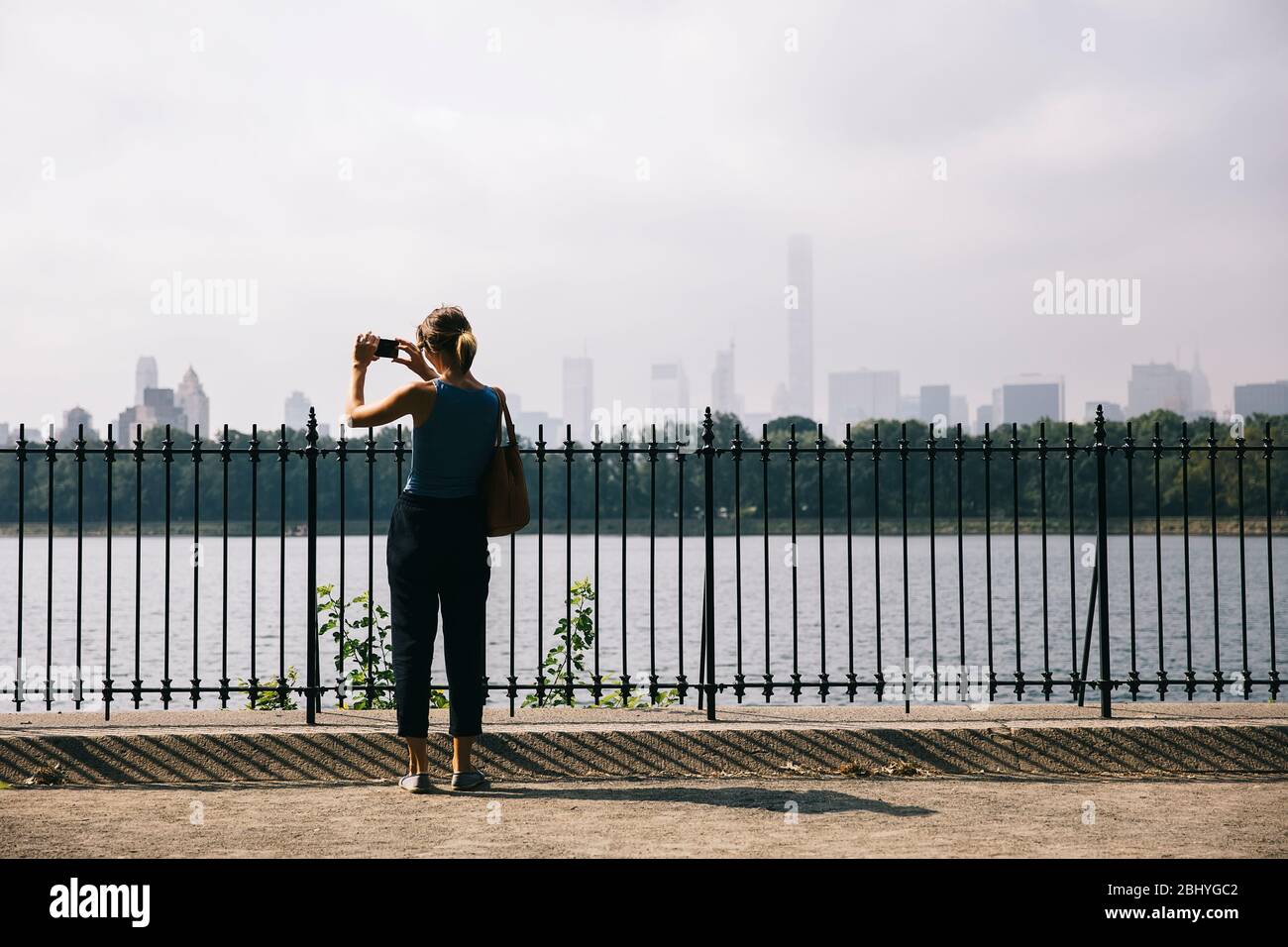 Junge Touristenfrau, die mit dem Handy die Skyline von New York City fotografiert Stockfoto