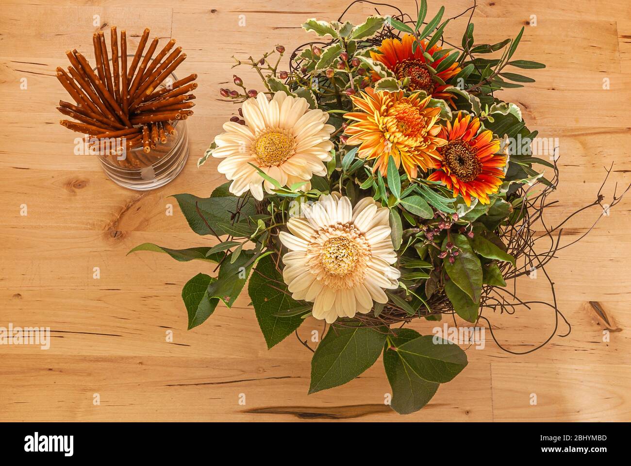 Das Stillleben des Blumenstraußes und des Glases der Salzstangen auf dem hölzernen Tisch. Stockfoto