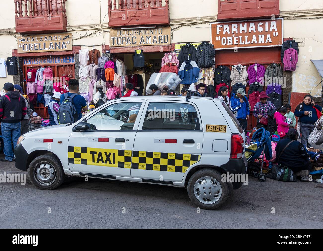 Lokales Taxi vor dem Bekleidungsstand und der Apotheke vor dem San Pedro Markt in Cusco, Peru Stockfoto