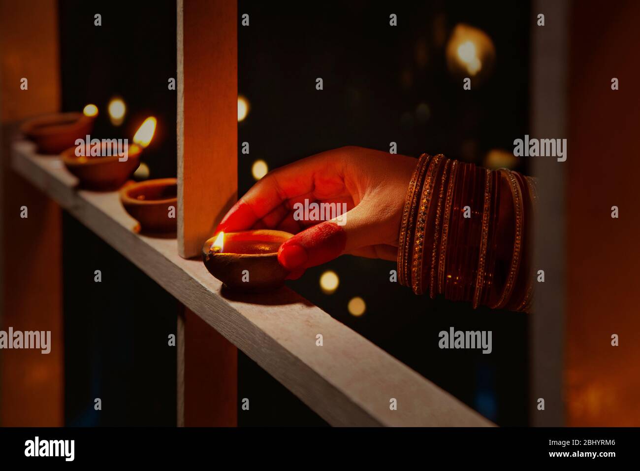 Junge Frau, die anlässlich von Diwali Diyas auf den Holzrahmen setzt. Stockfoto