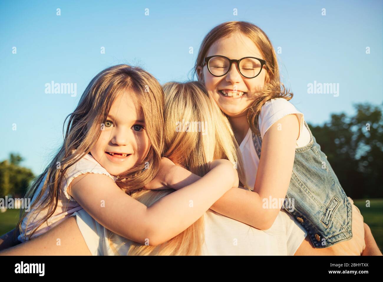 Zwei kleine Töchter umarmen ihre Mutter. Muttertag Konzept. Familie und Mutterschaft. Stockfoto