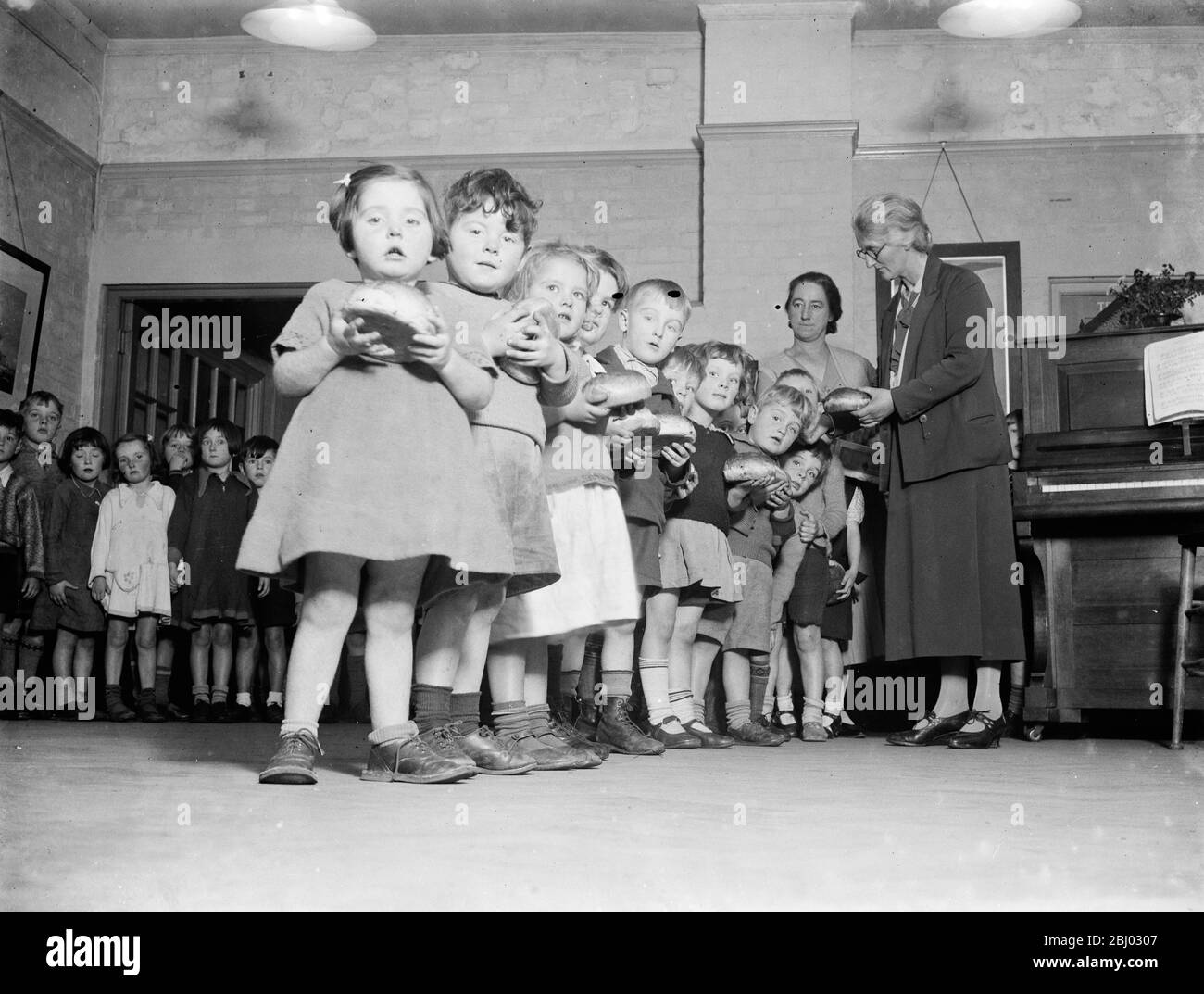 Kleine Kinder erhalten ihre Brötchen von der Guy Fawkes Charity . - 1935 Stockfoto