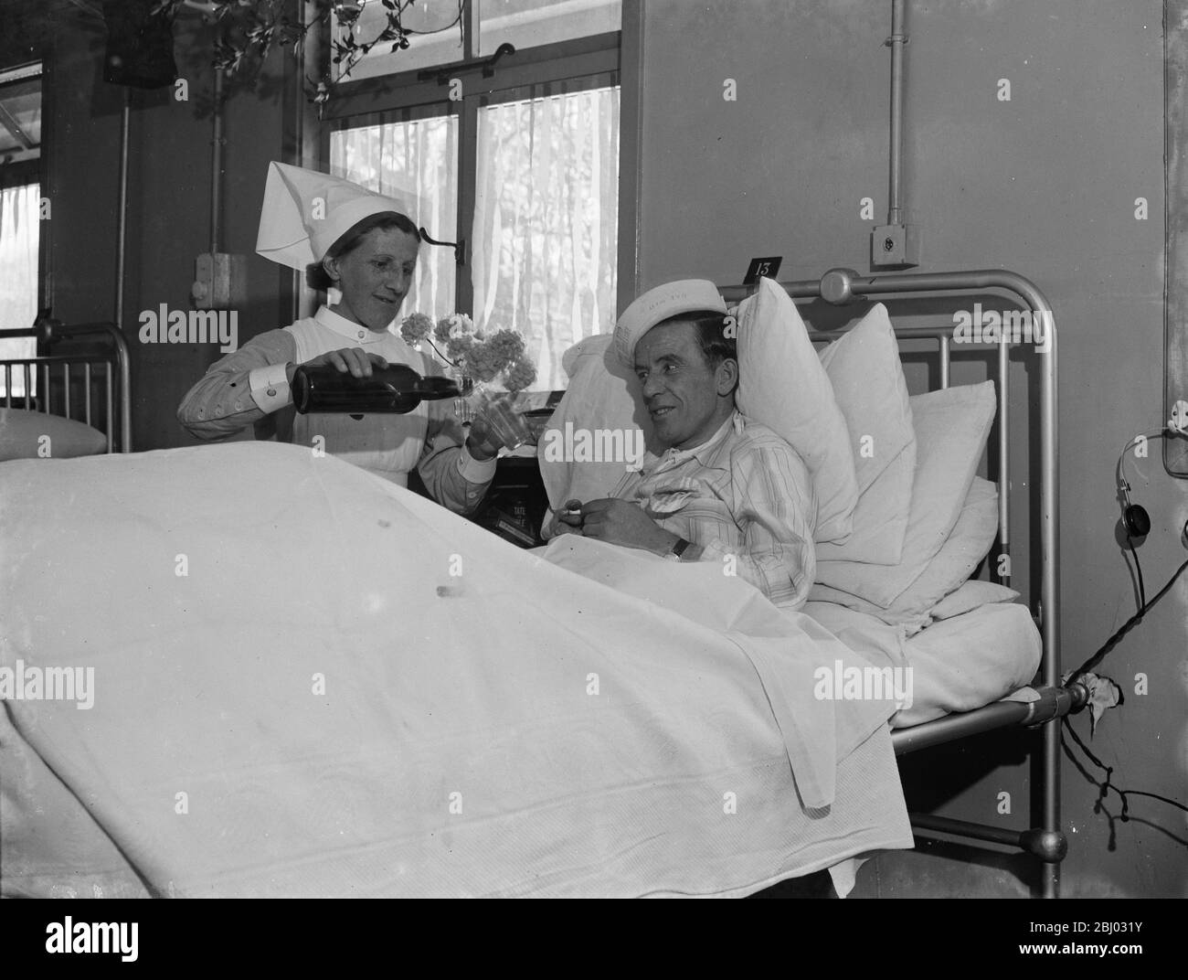 Weihnachten im Queens Hospital in Sidcup, Kent. - Patient wird von einer Krankenschwester ein Tipple gepoored. - 1938 Stockfoto