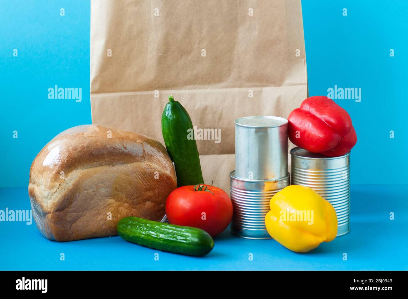 Papiertüte mit Lebensmittelzubehör auf blauem Hintergrund. Stockfoto