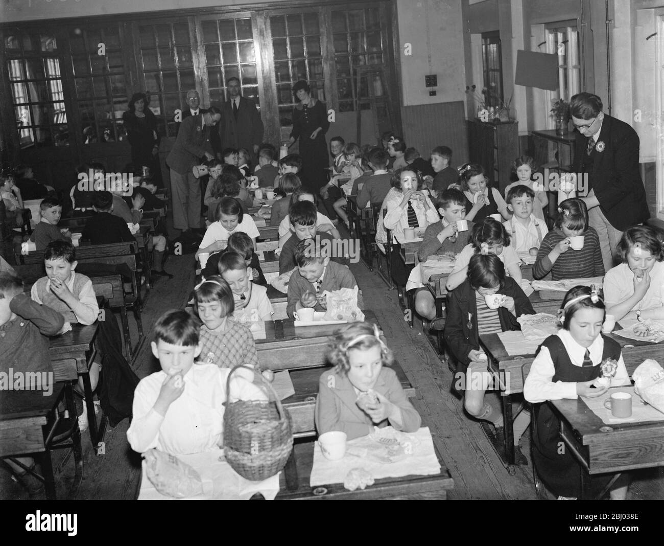 Krönungsschultee an einer Schule in Crayford, Kent, um die Krönung von König George VI zu feiern. Kinder trinken aus den Krönungsbechern, die sie gerade erhalten haben. - 10. Mai 1937 Stockfoto