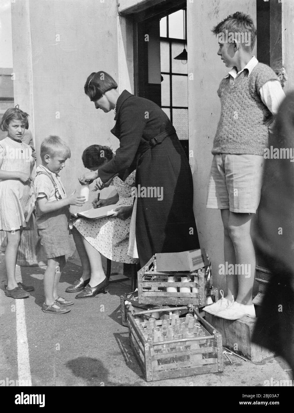 Kostenlose Milch für Kinder im Urlaub in Crayford, Kent. Eine Frau sammelt die leeren Flaschen. - 1939 Stockfoto