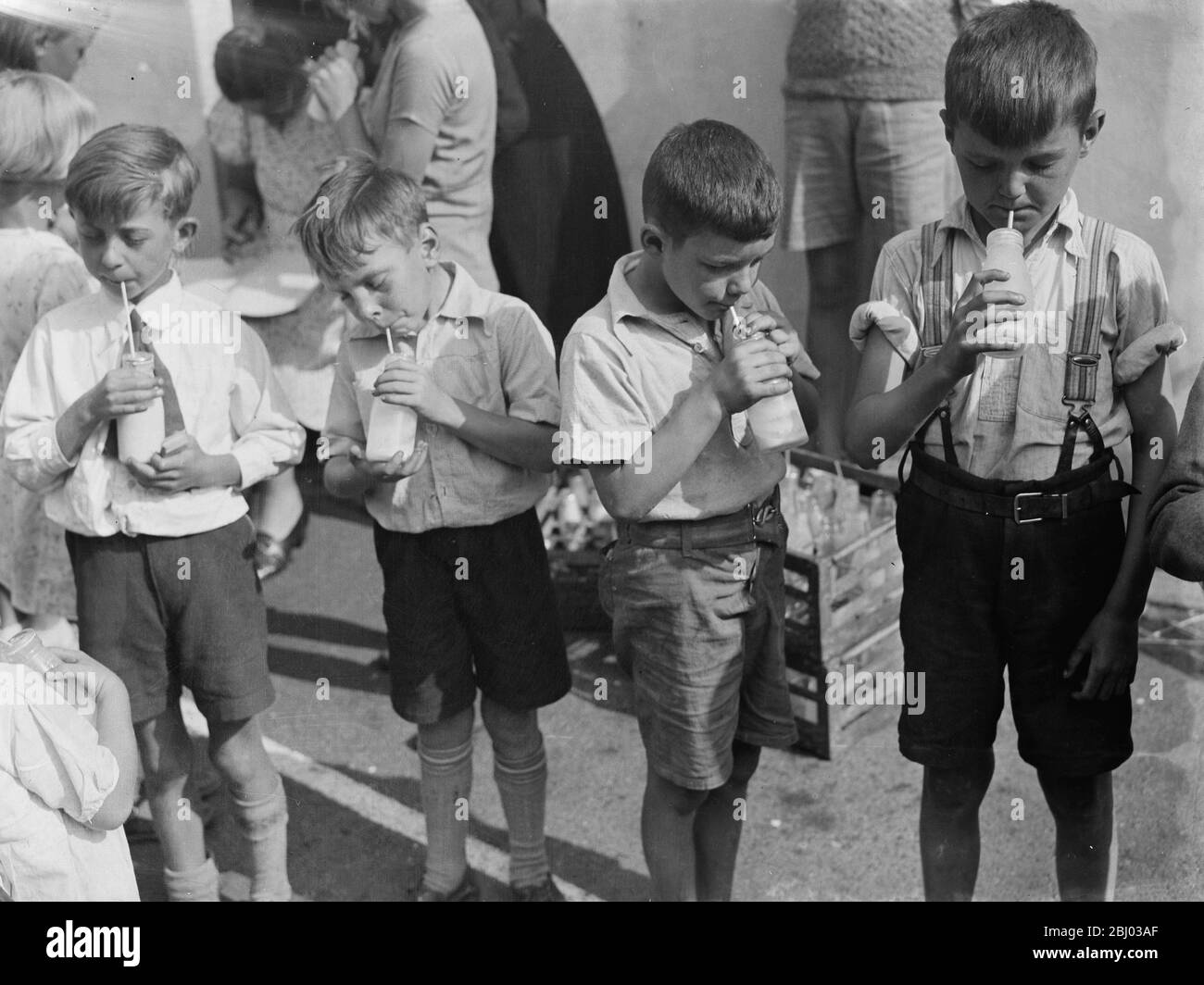 Kostenlose Milch für Kinder im Urlaub in Crayford, Kent. Jungs stehen in einer Reihe nippen ihre Milch. - 1939 Stockfoto