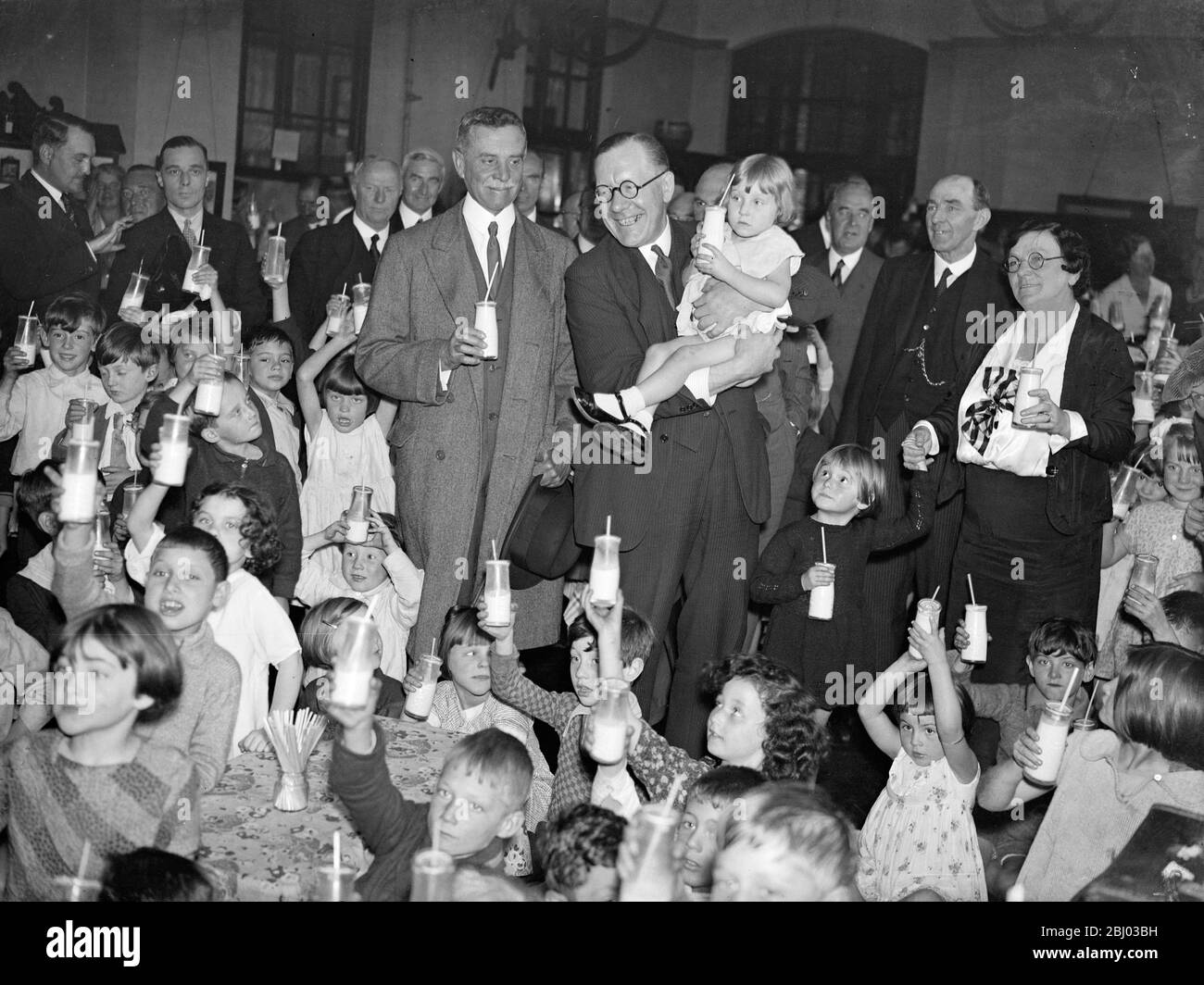 Walter Elliot Landwirtschaftsminister trinkt Milch mit Kindern an einer Londoner Schule. Herr Elliot und Herr Astor - 1. Oktober 1934 Stockfoto