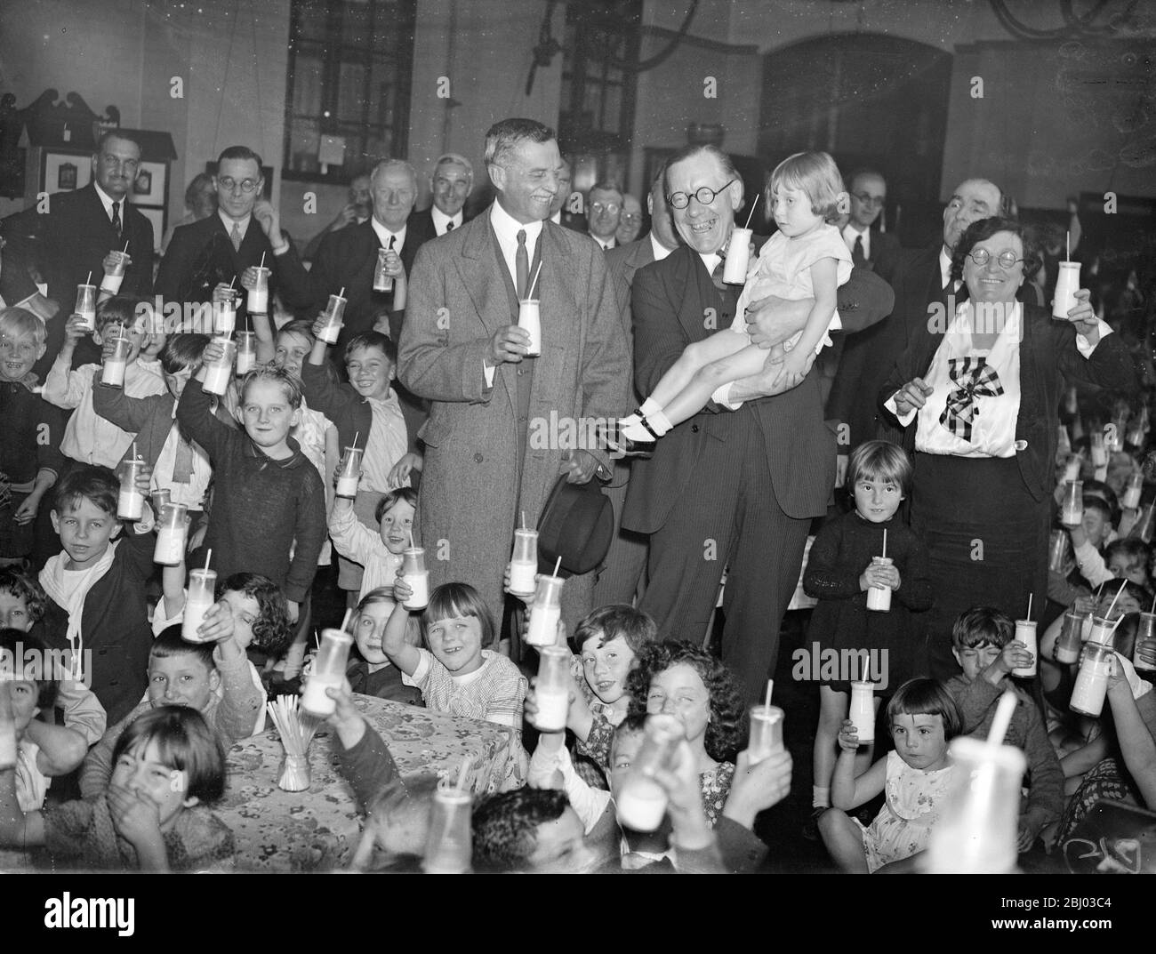 Walter Elliot Landwirtschaftsminister trinkt Milch mit Kindern an einer Londoner Schule. Herr Elliot und Herr Astor - 1. Oktober 1934 Stockfoto