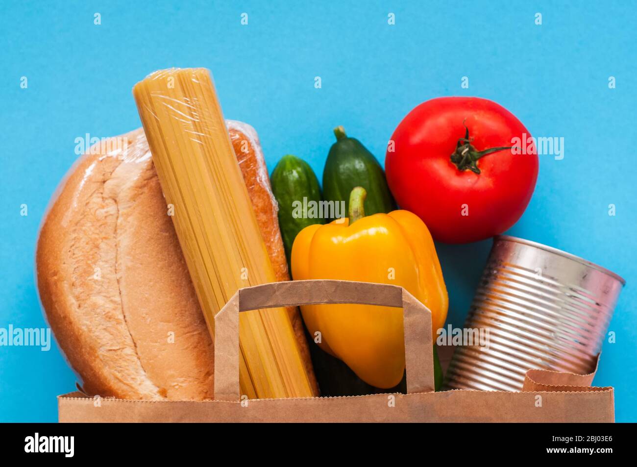 Papiertüte mit Lebensmittelzubehör auf blauem Hintergrund. Stockfoto