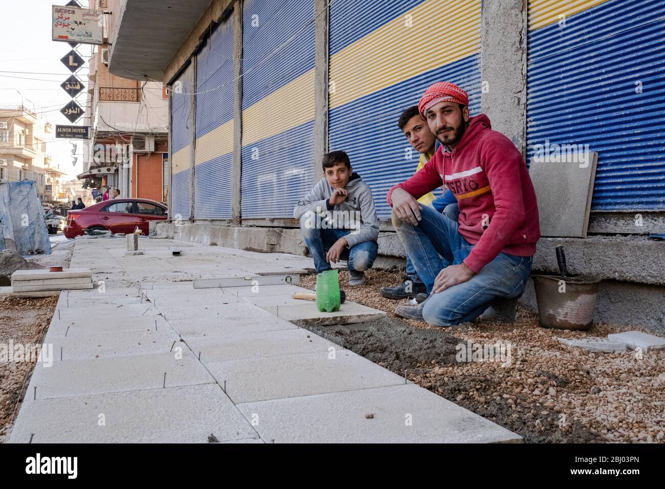 Junge Arbeiter bauen einen Bürgersteig in Qamischli, Syrien. Stockfoto