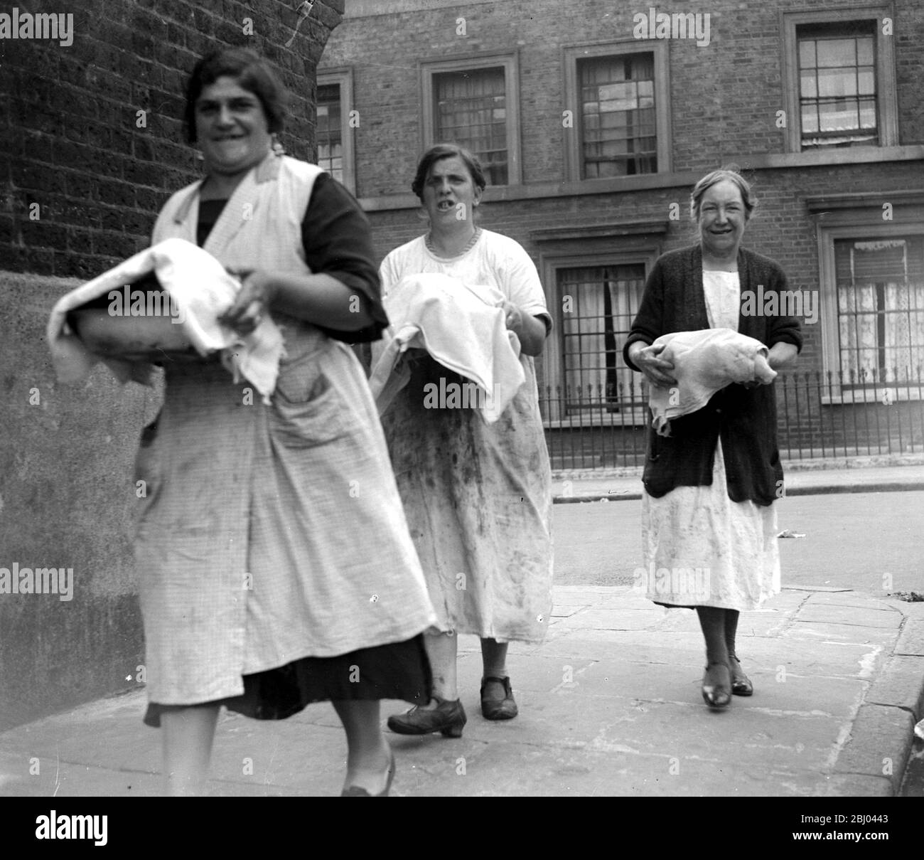 Hausfrauen, die im Gemeinschaftsofen im Londoner East End ein Abendessen mit nach Hause nehmen. - 1933 - Stockfoto