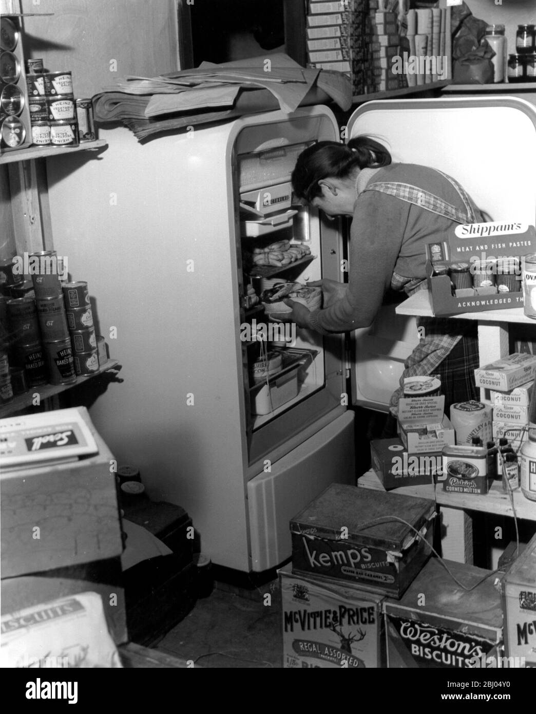 Großbritanniens einsamste Insel - im Dorfladen, mit Mrs A Till, die einige Waren aus dem einzigen Kühlschrank der Insel herausnimmt - es funktioniert mit Parafin. - 22. Juli 1957 Stockfoto